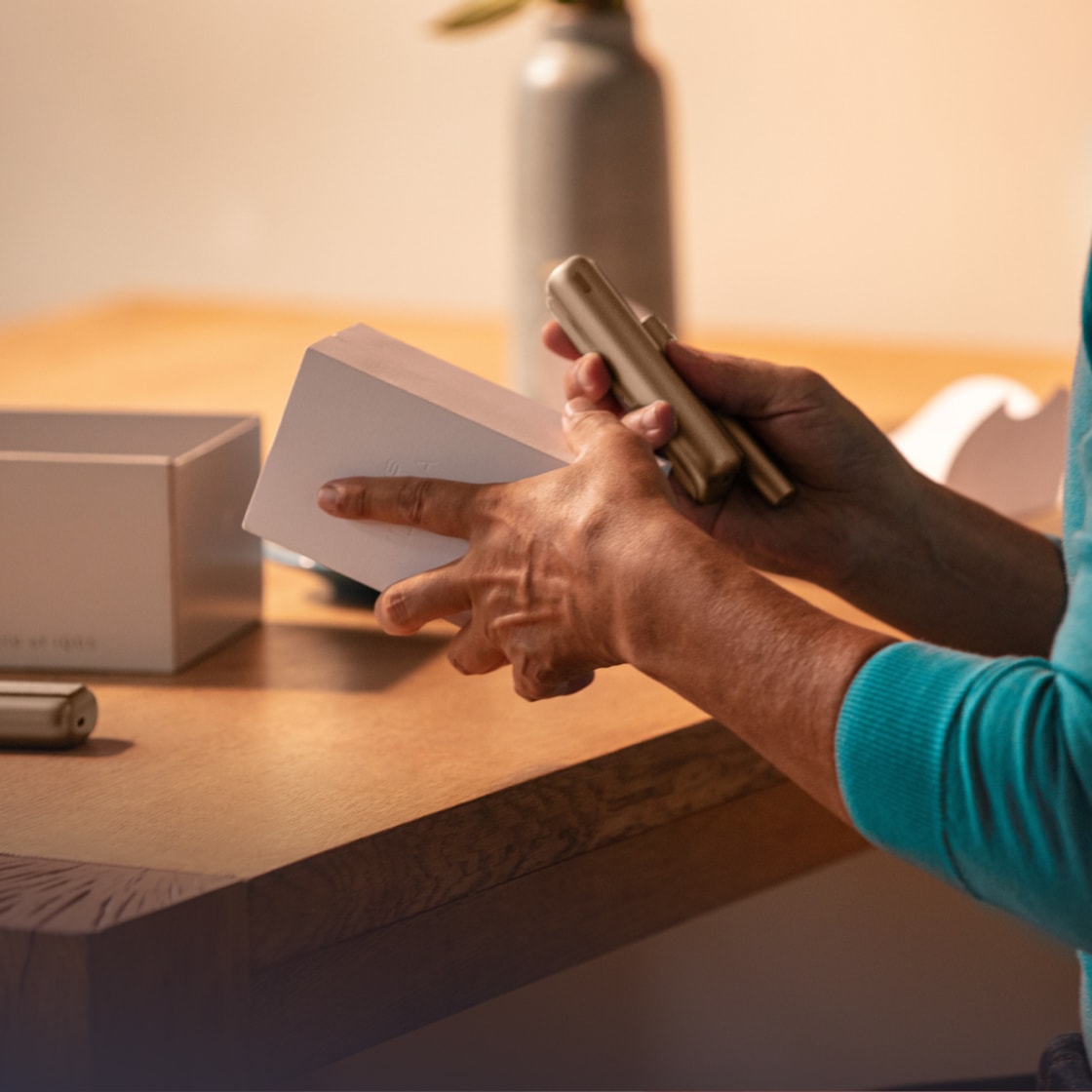 A person takes a new IQOS device from its packaging.